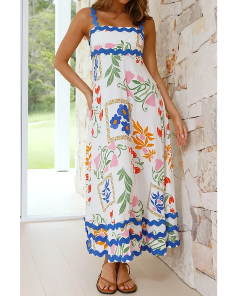 woman wearing floral resort wear dress with colorful floral patterns and blue trim maxi dress