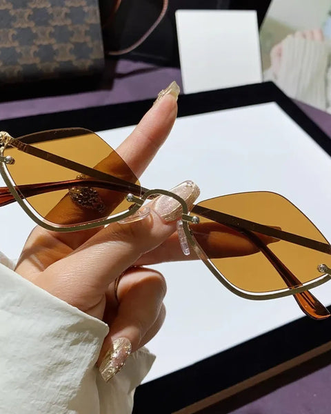 Trendsi glamorous vacation sunglasses with brown tinted lenses and gold metal frame held in hand