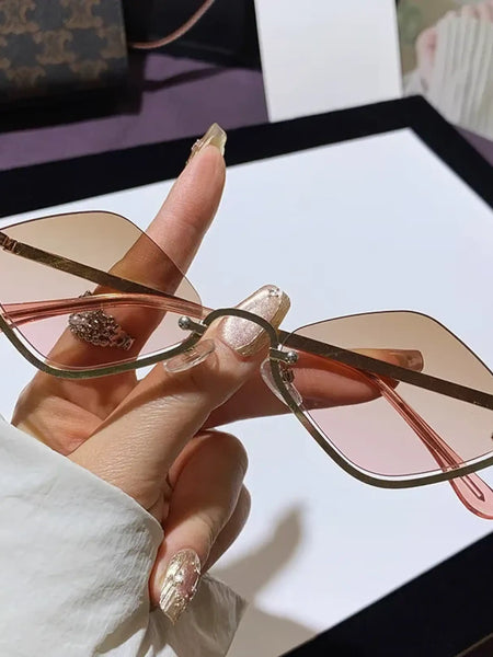 Trendsi glamorous vacation sunglasses with pink gradient lenses and gold wireframe held in hand