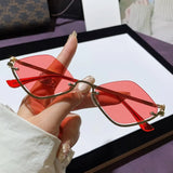 Trendsi glamorous vacation sunglasses with red tinted lenses and gold frame held by hand