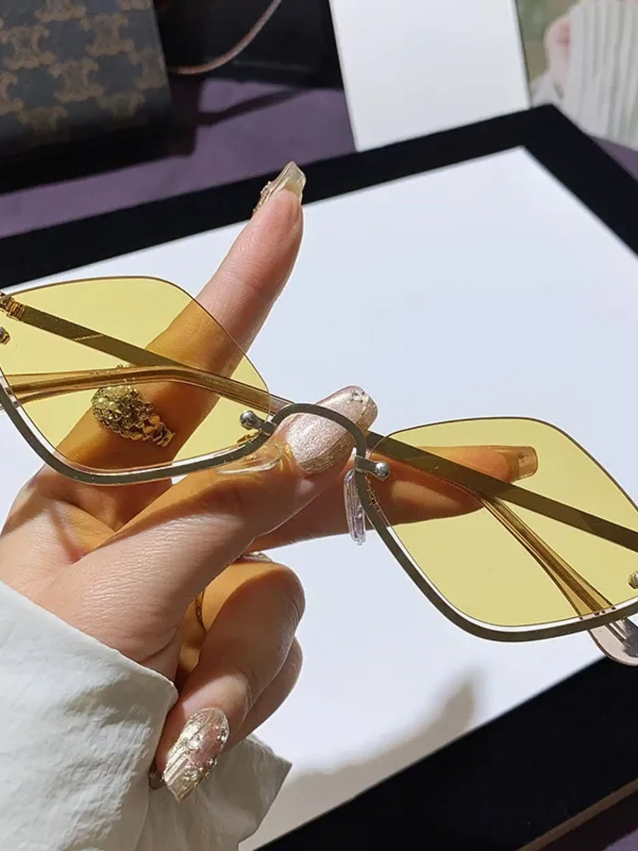 Trendsi glamorous vacation sunglasses with yellow tinted lenses and gold frame held by hand
