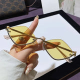 Trendsi glamorous vacation sunglasses with yellow tinted lenses and gold frame held by hand