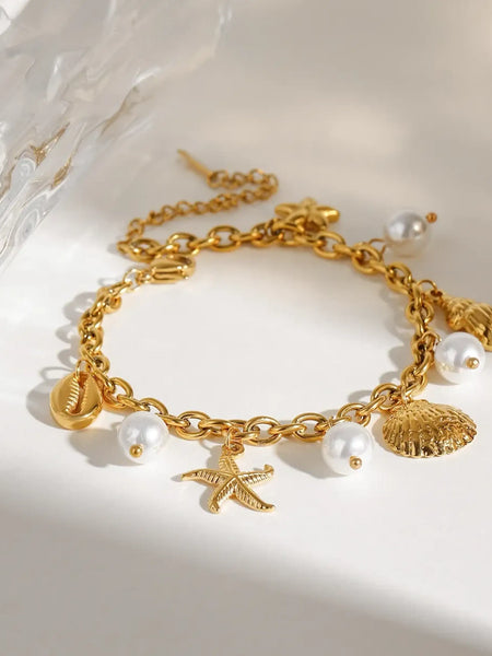 Gold ocean theme bracelet for women with gold shell charms and white pearl accents