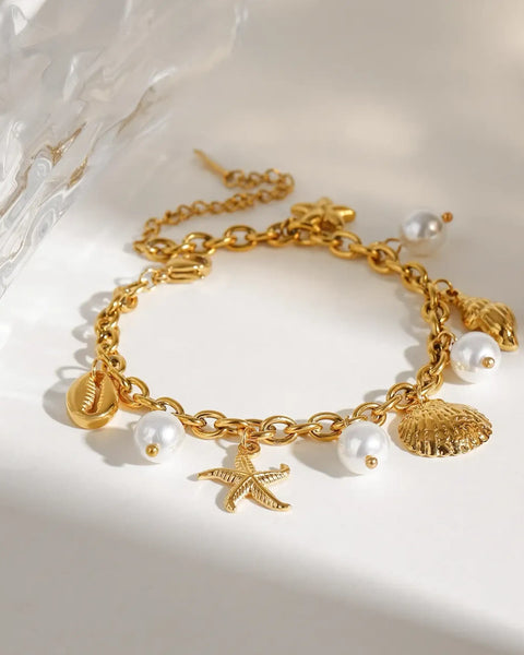 Gold ocean theme bracelet for women with gold shell charms and white pearl accents
