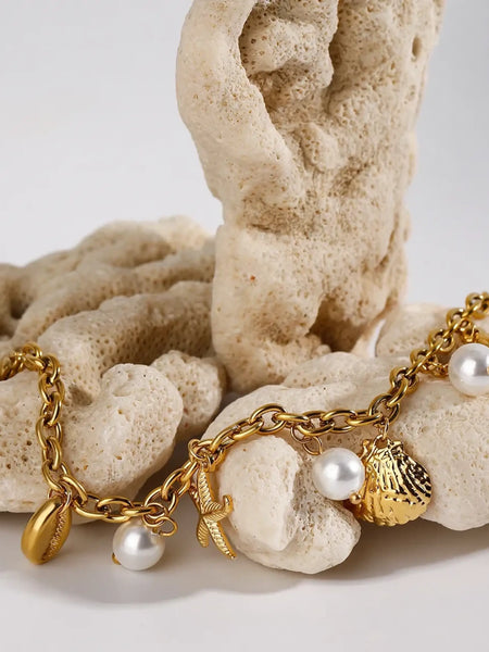 Gold ocean theme bracelet for women with gold chain, seashell, starfish charms, and pearl accents