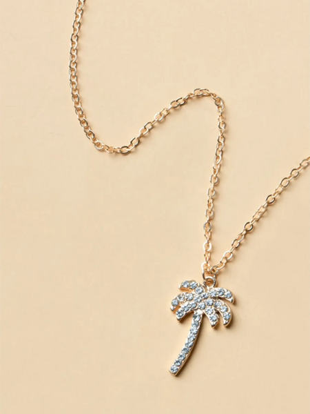 palm tree pendant necklace with sparkling stones and gold chain on beige background