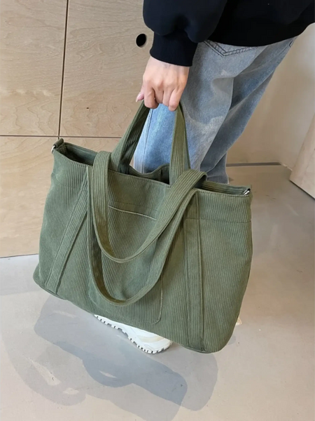 Lightweight Ladies duffle bag in olive green corduroy fabric held by a person wearing jeans and white shoes