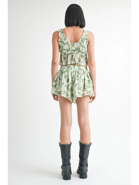 Back view of model wearing Emory Park green tropical flutter shorts with matching top and black boots
