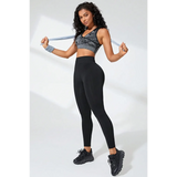 Woman wearing Babe Beachwear black high waisted leggings with black sports shoes and gray sports bra