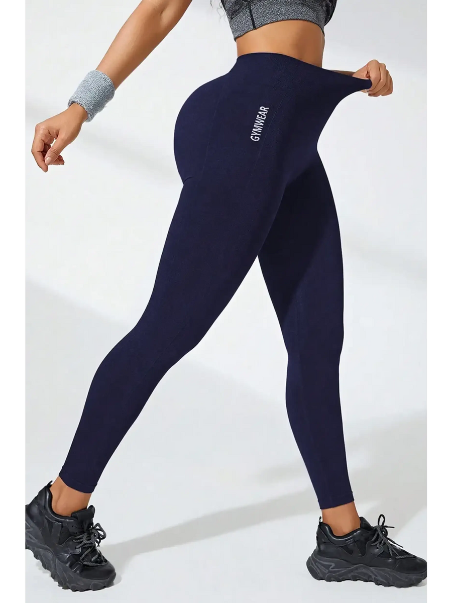 Babe Beachwear black high waisted leggings worn by woman stretching the waistband with athletic shoes