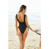 Beach Babes high hip black lace swimsuit worn by woman standing on sandy beach near ocean