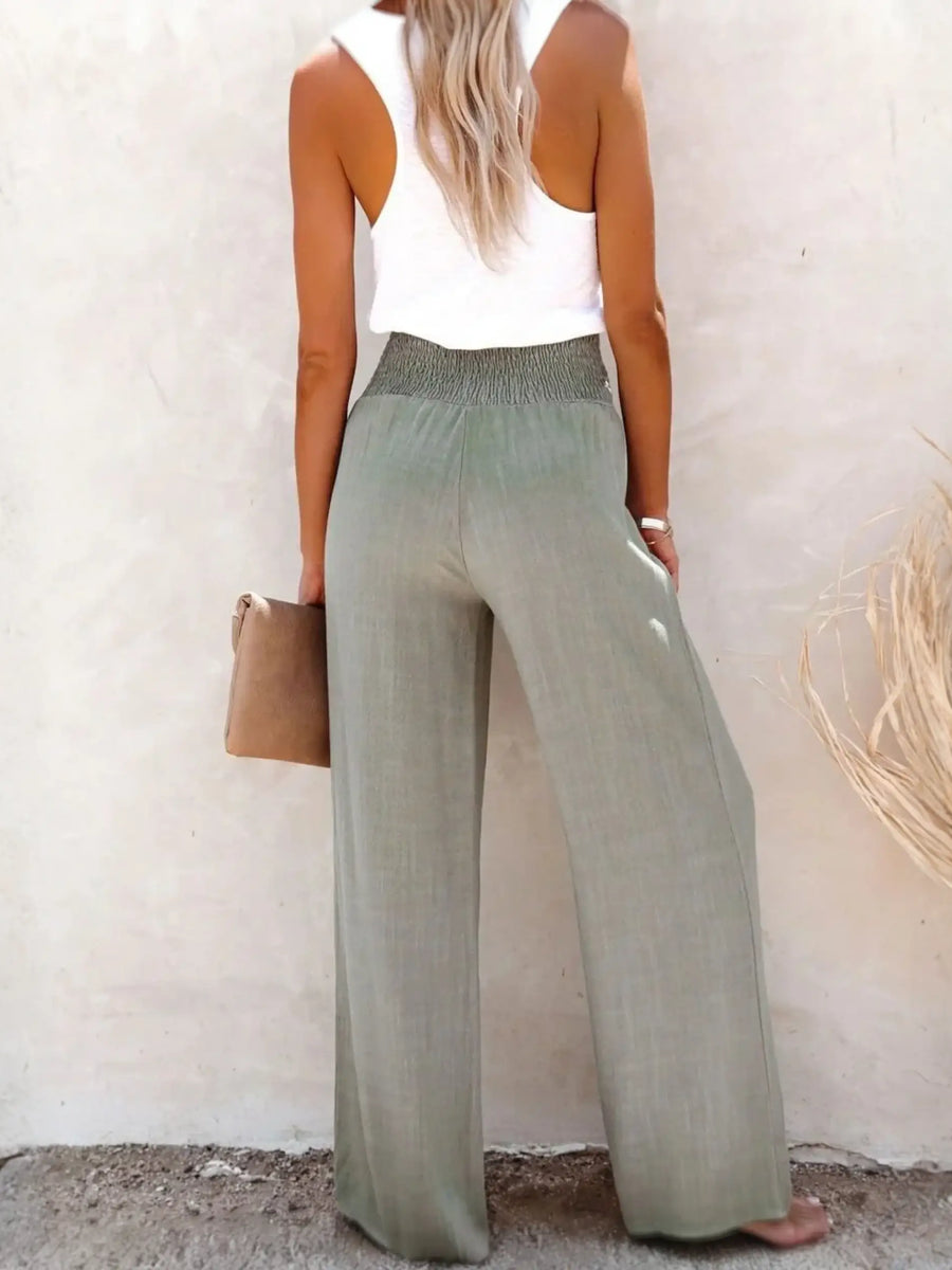 Woman wearing Babe Beachwaer high waisted beach pants set in light green with a white sleeveless top