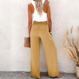 Back view of high waisted beach pants set in tan from Babe Beachwaer styled with white tank top and clutch