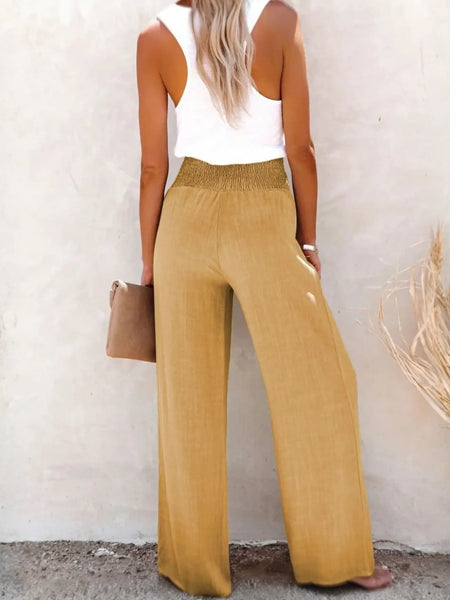 Back view of high waisted beach pants set in tan from Babe Beachwaer styled with white tank top and clutch