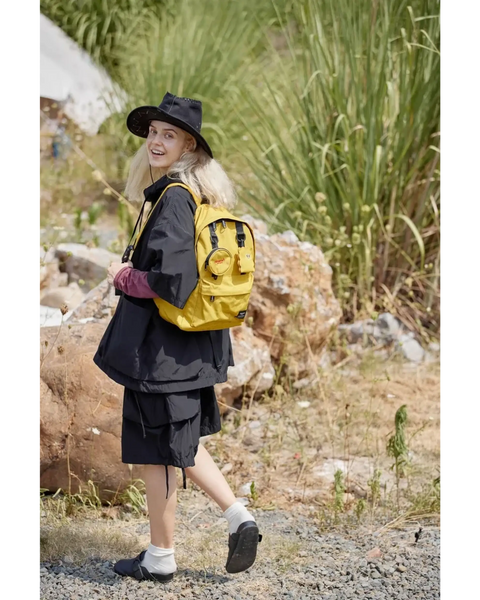 Woman wearing a yellow medium beach backpack for school or travel by Babe Beachwaer outdoors