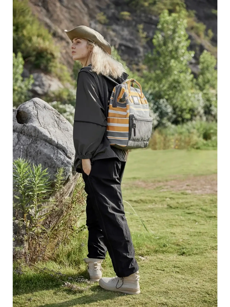Woman wearing Himwari Large waterproof backpack striped in outdoor nature setting with casual black outfit