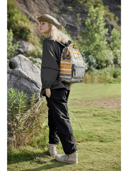 Woman wearing Himwari Large waterproof backpack striped in outdoor nature setting with casual black outfit