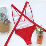 Hot Pink halter one piece swimsuit by Trendsi laid flat with woven bag and decorative plant