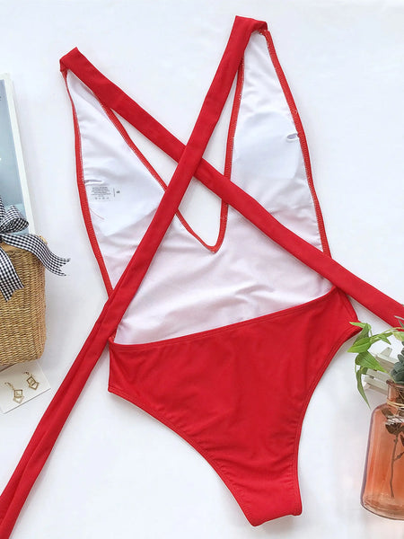Hot Pink halter one piece swimsuit by Trendsi laid flat with woven bag and decorative plant