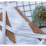 White swimsuit close-up on woven mat with flowers highlighting details for hot pink halter one piece