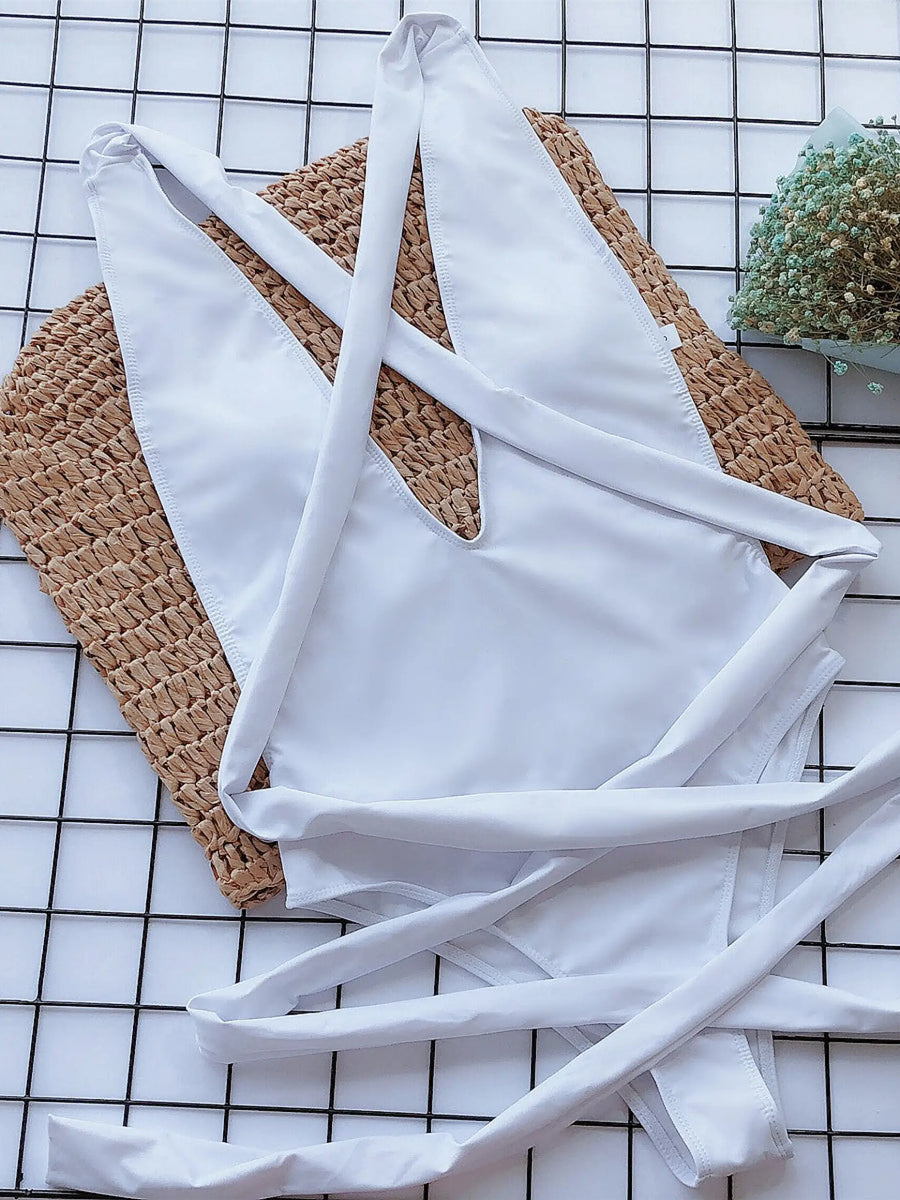 White halter one piece swimsuit laid flat on woven mat with flowers nearby by Trendsi