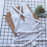 White halter one piece swimsuit laid flat on woven mat with flowers nearby by Trendsi