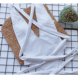 Trendsi white swimsuit laid flat with straps on woven mat and floral decoration background