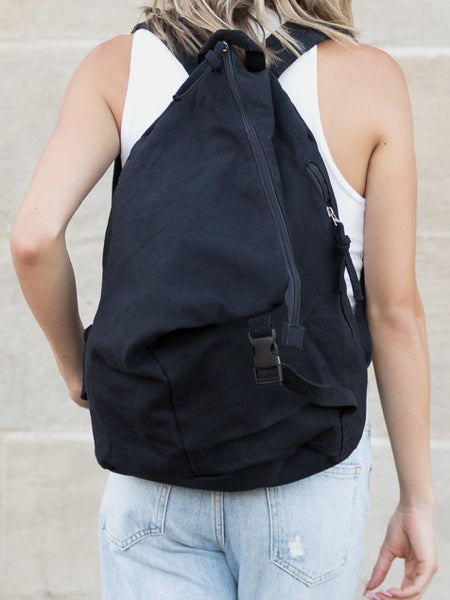 Babe Beachwaer Kai Asymetric Canvas Backpack in black worn by person in white tank top and jeans
