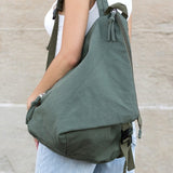 Kai Asymetric Canvas Backpack in olive green worn by a person with casual outfit