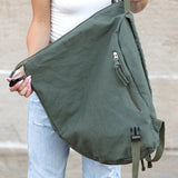 Kai Asymetric Canvas Backpack by Babe Beachwaer in olive green held by woman wearing white top and light jeans