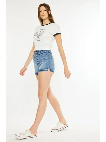 Woman wearing kancan button fly cutoff shorts in blue denim with white casual shoes and white graphic t shirt