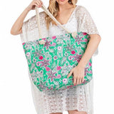 Woman holding large floral beach bag for women with green background and pink flowers from Babe Beachwear