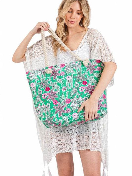 Woman holding large floral beach bag for women with green background and pink flowers from Babe Beachwear