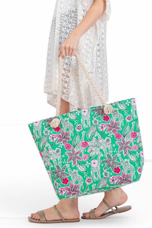 Large floral beach bag for women by Babe Beachwear with green background and pink flowers held by woman in white lace dress