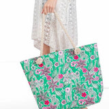 Large floral beach bag for women by Babe Beachwear with green background and pink flowers held by woman in white lace dress