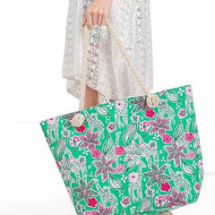 Large floral beach bag for women by Babe Beachwear with green background and pink flowers held by woman in white lace dress