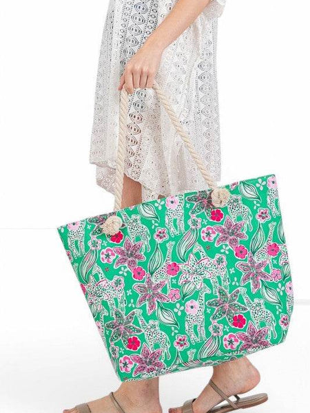 Large floral beach bag for women by Babe Beachwear with green background and pink flowers held by woman in white lace dress