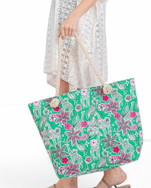 Large floral beach bag for women by Babe Beachwear with green background and pink flowers held by woman in white lace dress