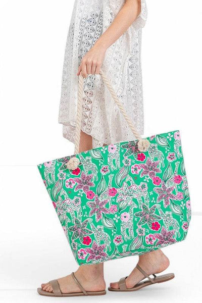 Large floral beach bag for women by Babe Beachwear with green background and pink flowers held by woman in white lace dress