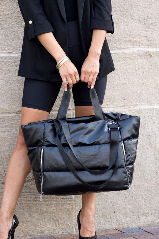 Large lightweight puffer weekends black bag by Babe Beachwear held by woman in black outfit