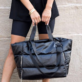 Large lightweight puffer weekends black bag by Babe Beachwear held by woman in black outfit