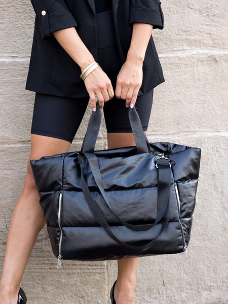 Large lightweight puffer weekends black bag by Babe Beachwear held by woman in black outfit