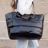 Black large lightweight puffer weekends bag carried by a woman with adjustable shoulder strap