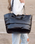Black large lightweight puffer weekends bag carried by a woman with adjustable shoulder strap