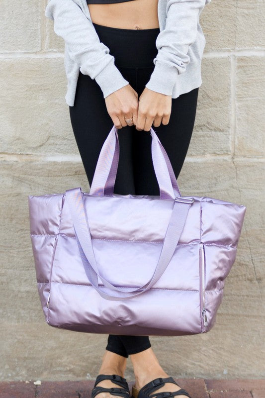 Babe Beachwear large lightweight puffer weekends bag in shiny lavender held by person in casual wear