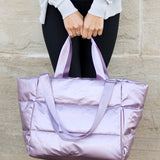 Babe Beachwear large lightweight puffer weekends bag in shiny lavender held by person in casual wear