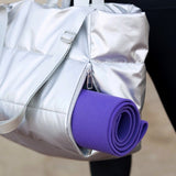 Babe Beachwear large lightweight puffer weekends bag in silver with side zipper holding a purple yoga mat
