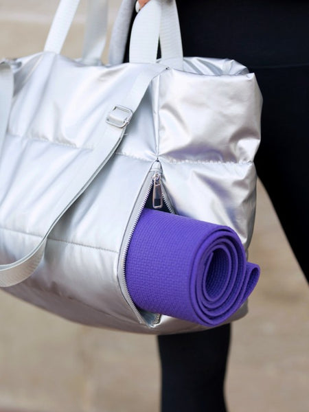 Babe Beachwear large lightweight puffer weekends bag in silver with side zipper holding a purple yoga mat