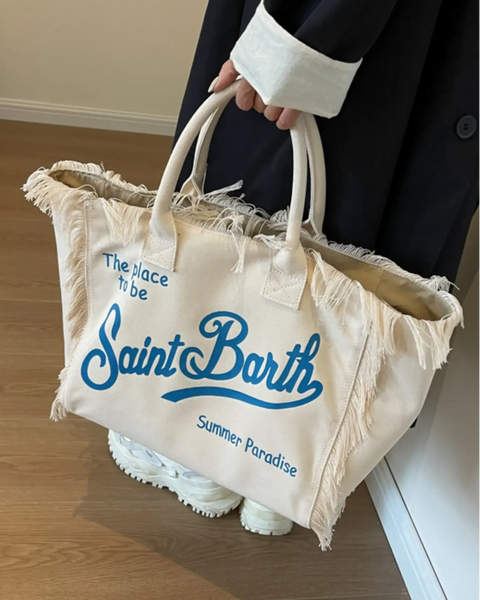 Large resort tote bag with fringe in cream color featuring blue Saint Barth text and double handles