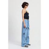 Emory Park laser cutout cotton beach pants in light blue wide leg style worn with black tank and sneakers
